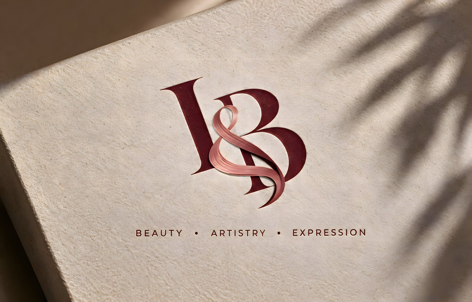 Ink&Blush I&B symbol embossed on warm textured surface with Beauty · Artistry · Expression tagline
